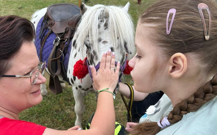 Dziecko głaszcze konia, radosne chwile na świeżym powietrzu.
