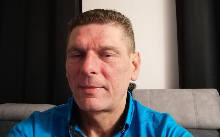 Mężczyzna w niebieskiej koszuli, siedzący na kanapie.