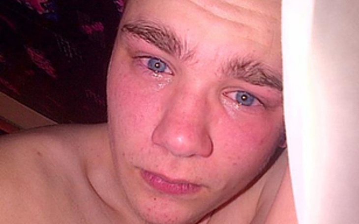 Młody mężczyzna leżący na łóżku, z wyrazem smutku na twarzy.