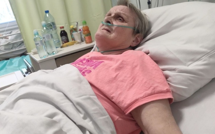 Kobieta leżąca w łóżku szpitalnym, wygląda na zmęczoną.