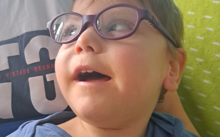 Chłopiec w okularach, uśmiecha się i wygląda na szczęśliwego.