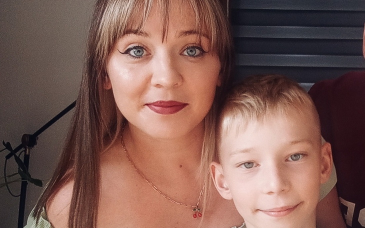 Portret matki z synem, oboje uśmiechnięci w domowym otoczeniu.