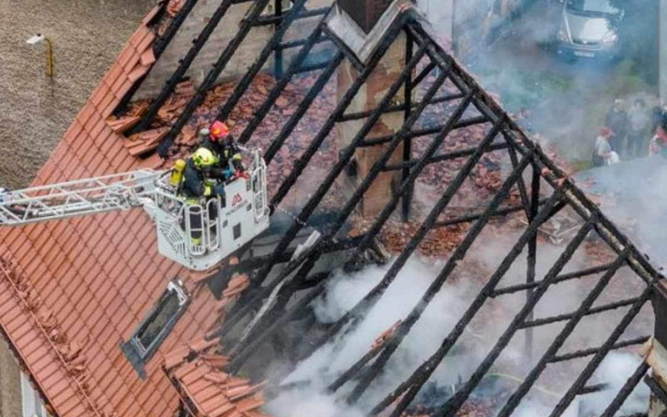 Strażacy gaszą pożar dachu budynku.