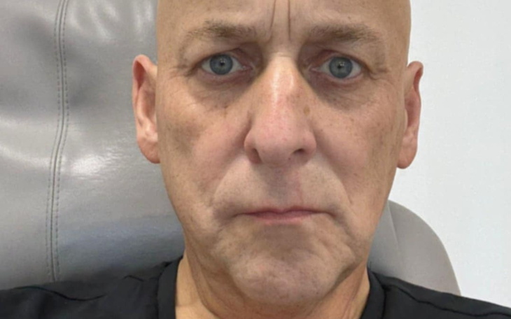 Mężczyzna z poważnym wyrazem twarzy siedzi w fotelu.