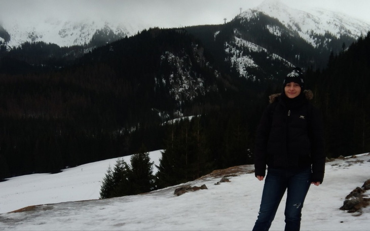 Kobieta na tle górskiego krajobrazu pokrytego śniegiem.