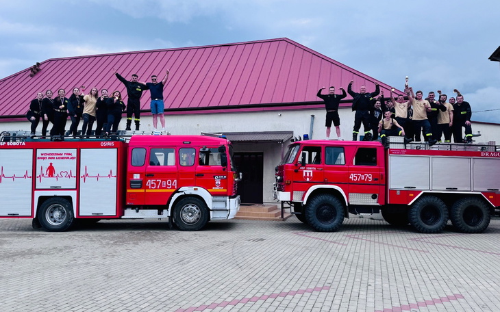 Grupa ludzi na dwóch wozach strażackich, radosne chwile.