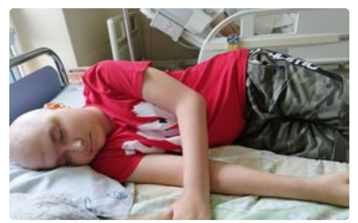 Chłopiec leżący w szpitalnym łóżku, śpiący.