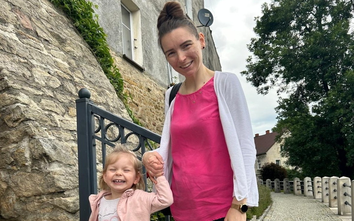 Matka z uśmiechniętą córką na tle kamiennego muru.