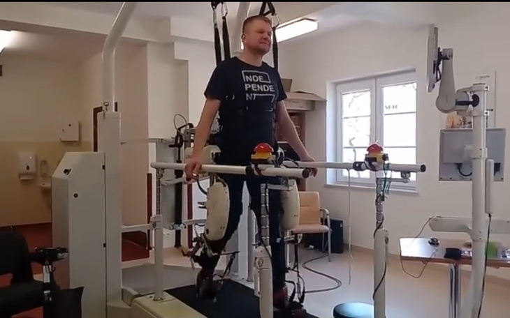 Mężczyzna w urządzeniu rehabilitacyjnym, uczący się chodzić.