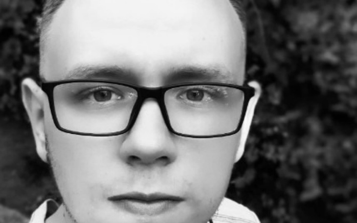 Czarno-białe zdjęcie młodego mężczyzny w okularach.