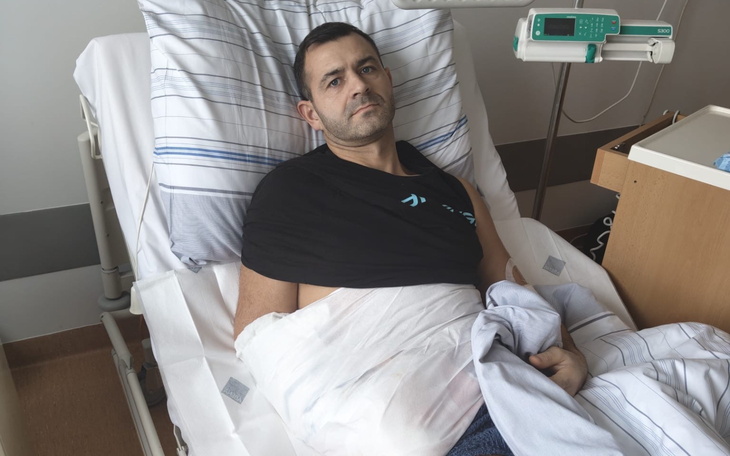 Mężczyzna w szpitalu z opatrunkiem na ramieniu.