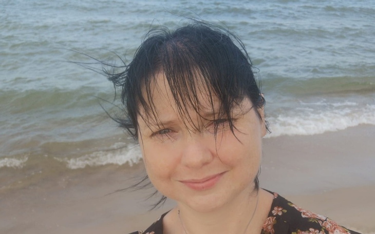 Kobieta z wiatrem we włosach na plaży.