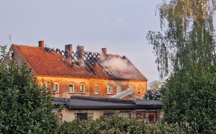Zniszczony budynek po pożarze, z dymem unoszącym się z dachu.