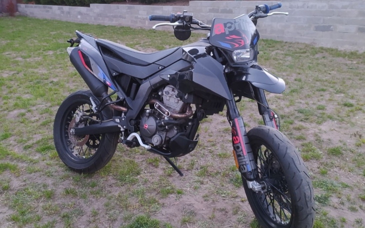 Motocykl terenowy zaparkowany na trawie, gotowy do jazdy.