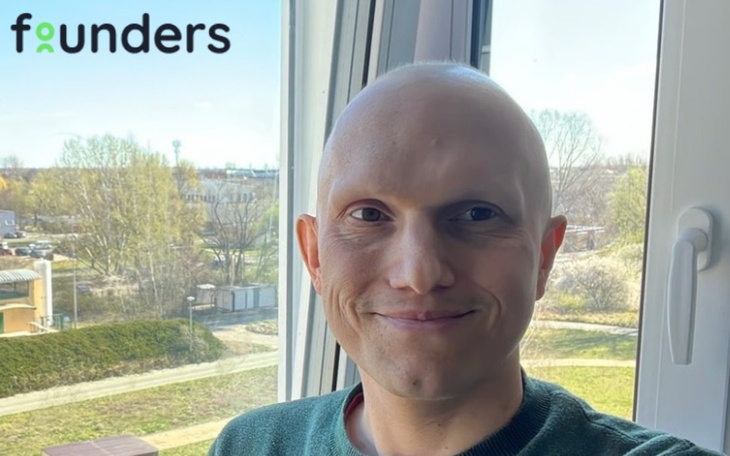 Mężczyzna z uśmiechem, stojący przy oknie.