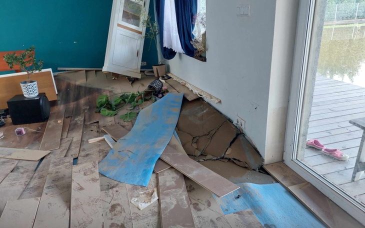 Zniszczone wnętrze domu, z uszkodzoną podłogą i meblami.