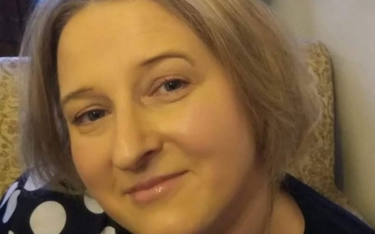 Portret kobiety z uśmiechem, siedzącej na kanapie.