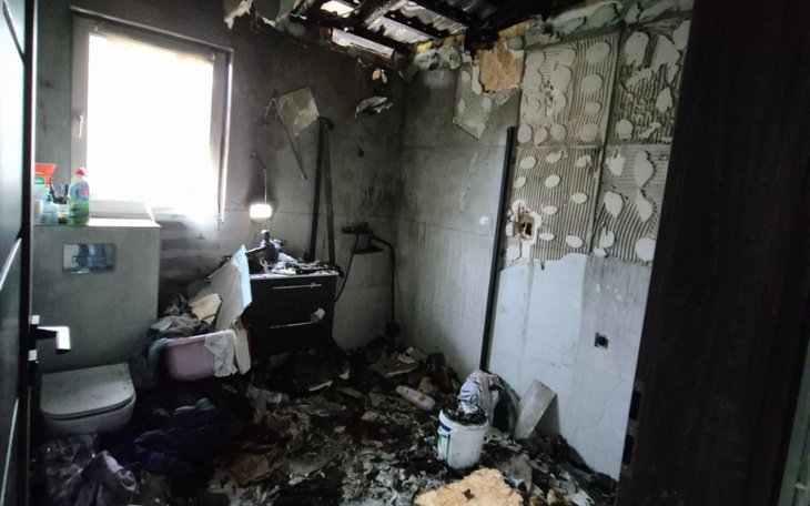 Zniszczona łazienka po pożarze, z bałaganem i uszkodzeniami.