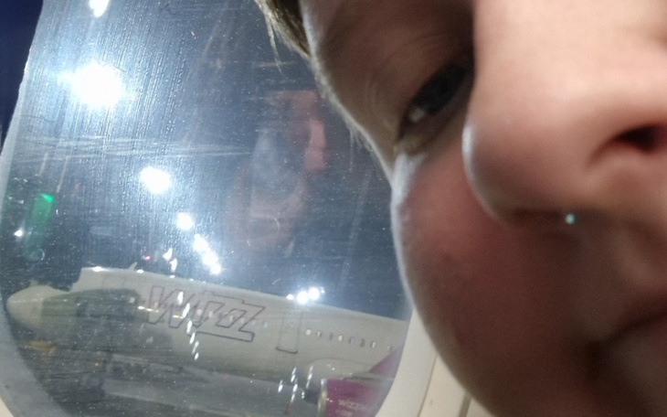 Zdjęcie z samolotem Wizz Air w tle, z bliskim ujęciem twarzy.