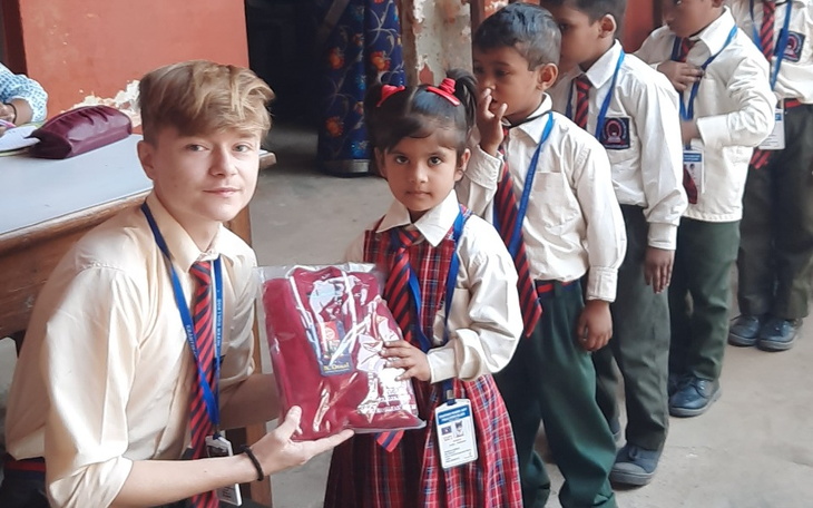 Dziecko w mundurku szkolnym odbierające nagrodę.