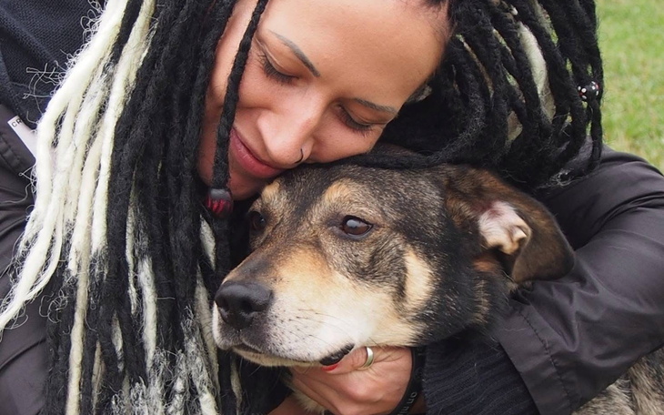 Kobieta przytulająca psa, wyrażająca miłość i troskę.