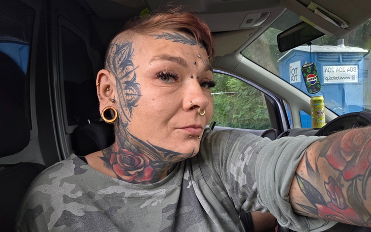 Osoba z tatuażami, pozująca w samochodzie.