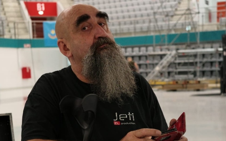 Mężczyzna z długą brodą, trzymający telefon w ręku.