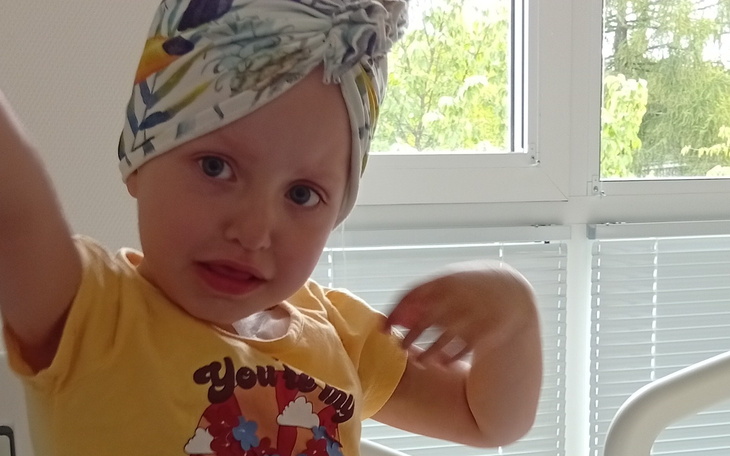 Mała dziewczynka w żółtej koszulce z chustą na głowie.