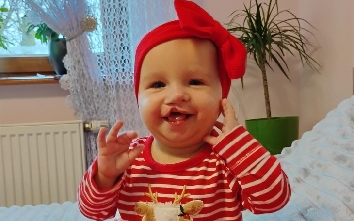 Uśmiechnięte dziecko w czerwonej opasce na głowie.