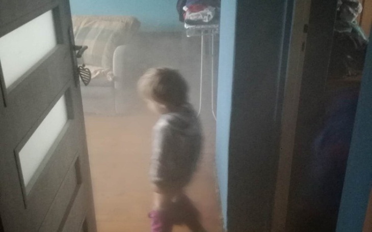 Dziecko w dymie, przechodzące przez drzwi.