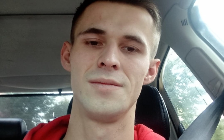 Mężczyzna w samochodzie, uśmiechający się do kamery.