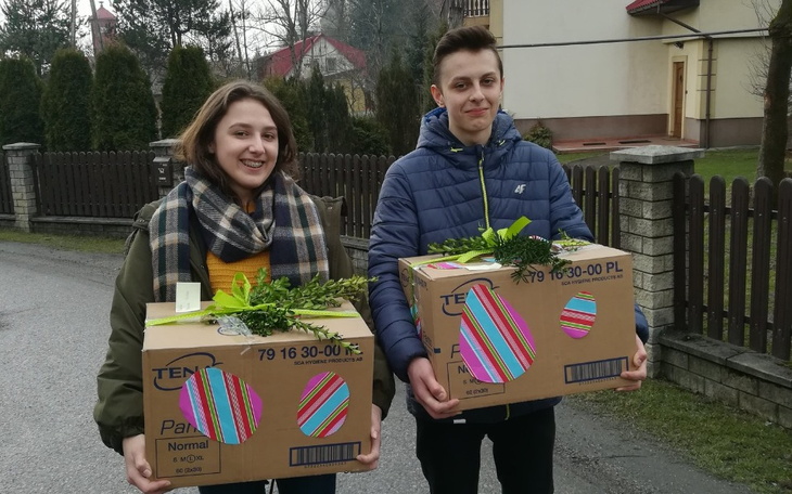 Młodzi ludzie niosący kartony z roślinami.