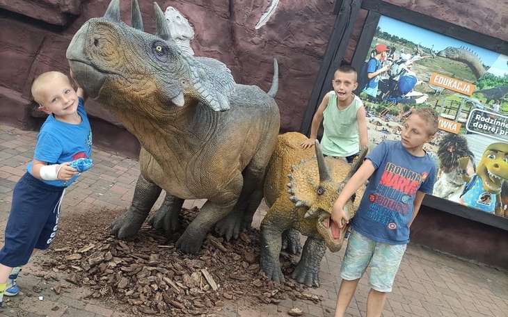 Dzieci bawiące się przy dinozaurach w parku rozrywki.