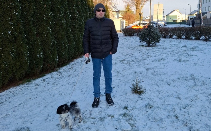 Mężczyzna spacerujący z psem w zimowym otoczeniu.