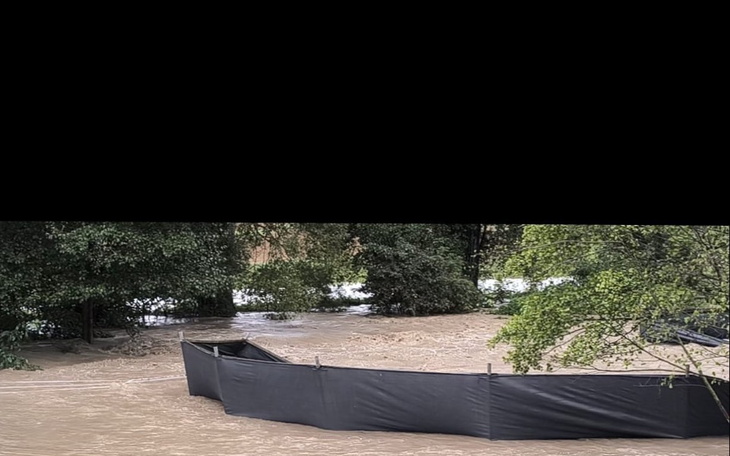 Zalany teren z drzewami i ogrodzeniem.