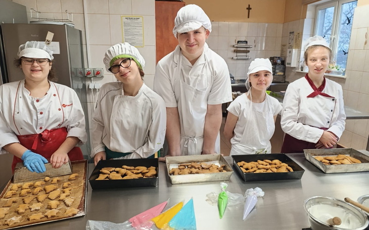 Grupa młodych kucharzy w kuchni, prezentują wypieki.