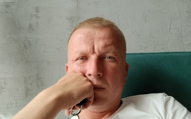 Mężczyzna z zamyśloną miną, trzymający rękę przy twarzy.