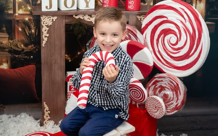 Chłopiec trzymający cukierka w otoczeniu słodyczy.