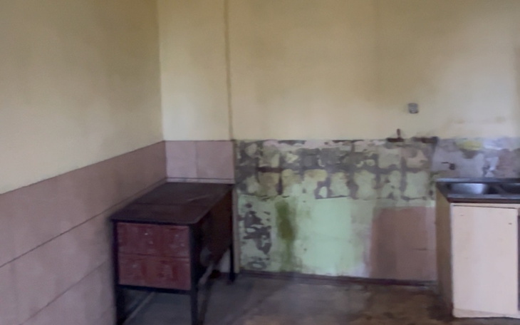 Pusty, zaniedbany pokój z meblami i odrapanymi ścianami.