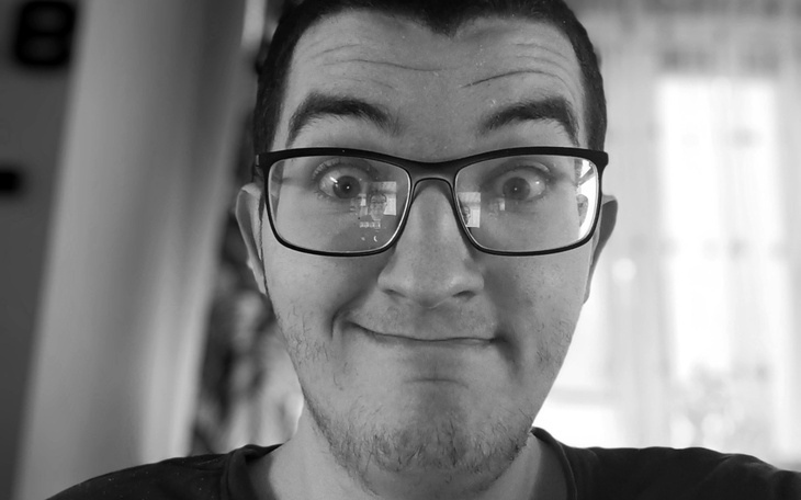 Mężczyzna w okularach, uśmiechający się do kamery.