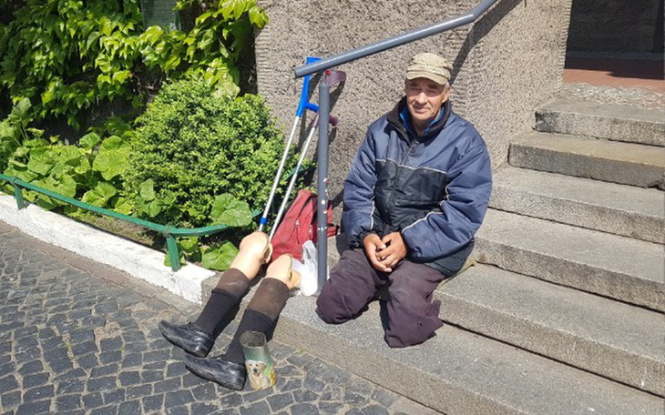 Mężczyzna siedzi obok rzeźby, z uśmiechem na twarzy.