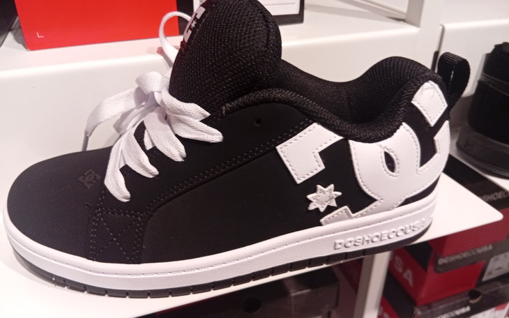 Czarne buty sportowe z białymi detalami na półce.
