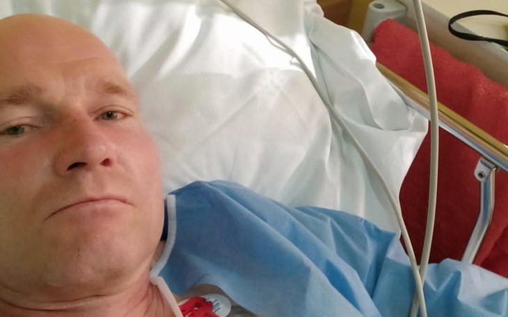 Mężczyzna w szpitalnym łóżku, w szlafroku.