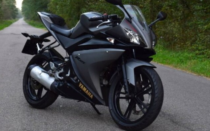 Motocykl sportowy na drodze w otoczeniu zieleni.