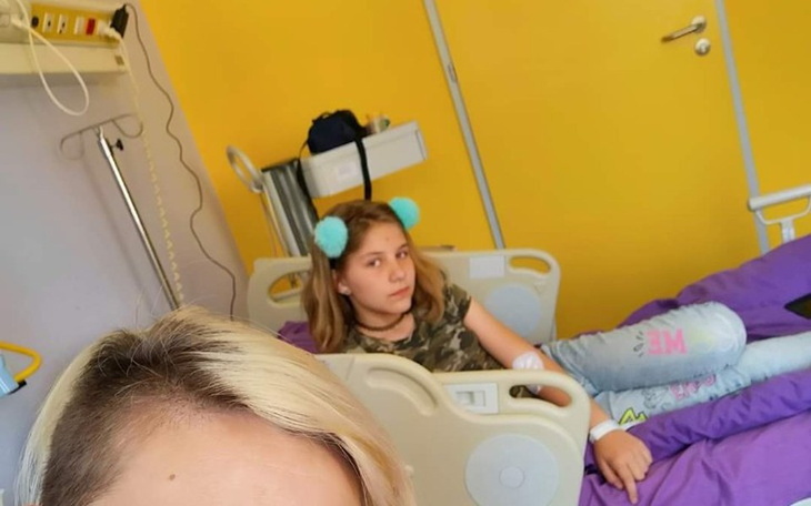 Dziewczyna w szpitalnym łóżku, z niebieskimi pomponami na uszach.