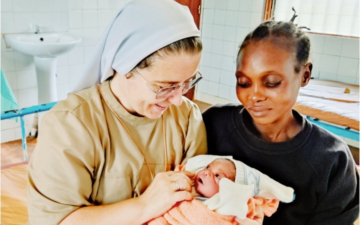 Siostra trzyma noworodka w ramionach, obok matka dziecka.