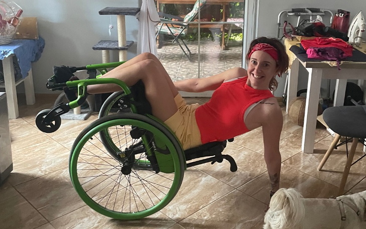 Kobieta w wózku inwalidzkim, uśmiechająca się w domu.