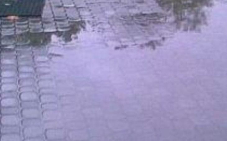 Odbicie chmur w kałuży na kostce brukowej po deszczu.