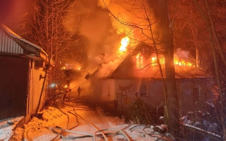 Pożar w budynku, strażacy walczą z ogniem w zimowej scenerii.