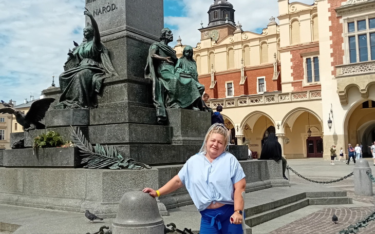 Kobieta pozująca przy pomniku w Krakowie.